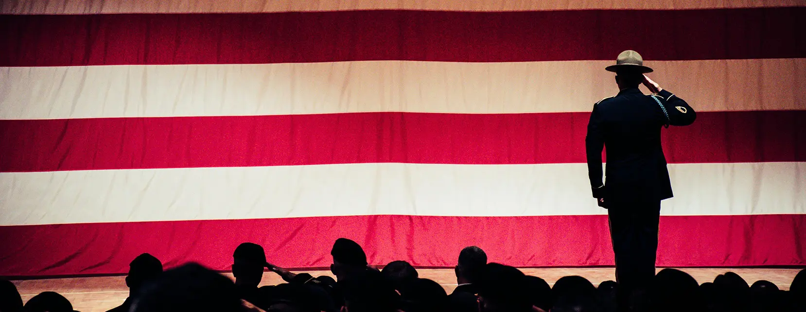 A large american flag hanging on the side of a building.