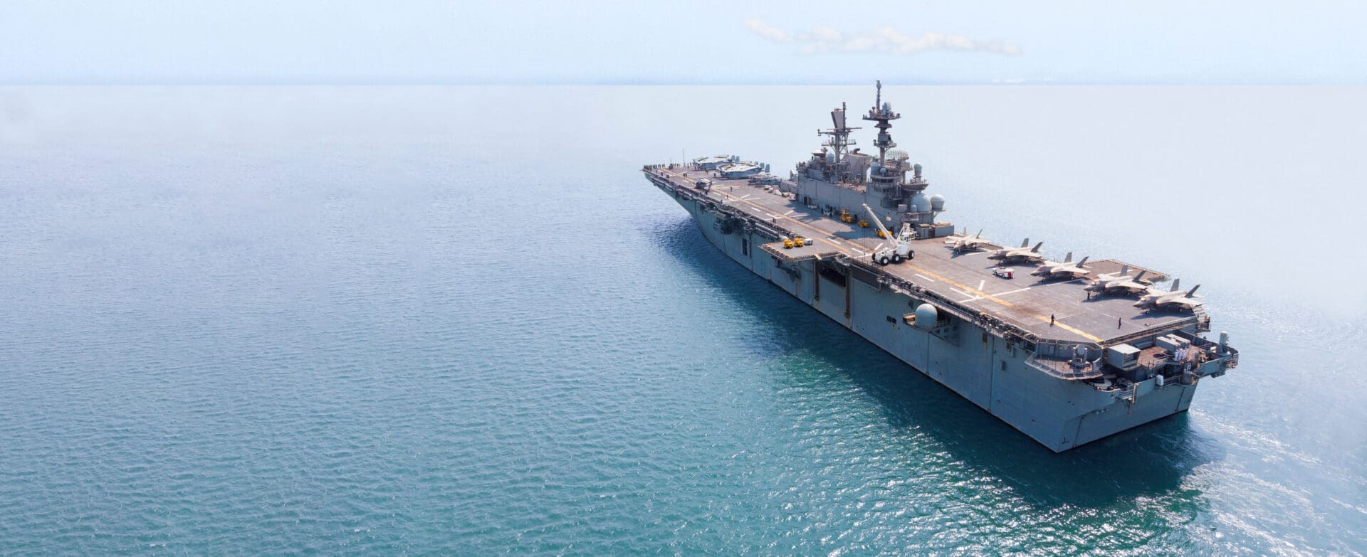 A large aircraft carrier in the middle of the ocean.